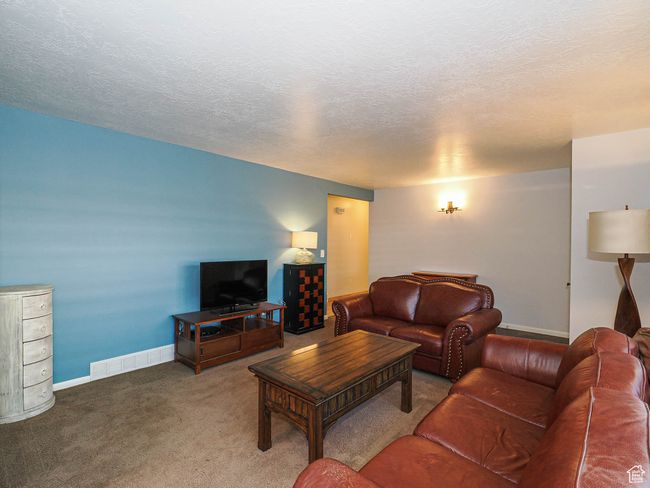 Carpeted living area with a textured ceiling and baseboards | Image 7