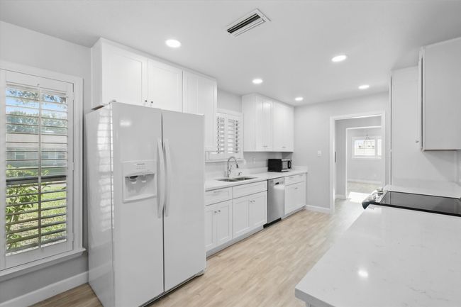 Kitchen with a wealth of natural light, stainless steel appliances, visible vents, and a sink | Image 8