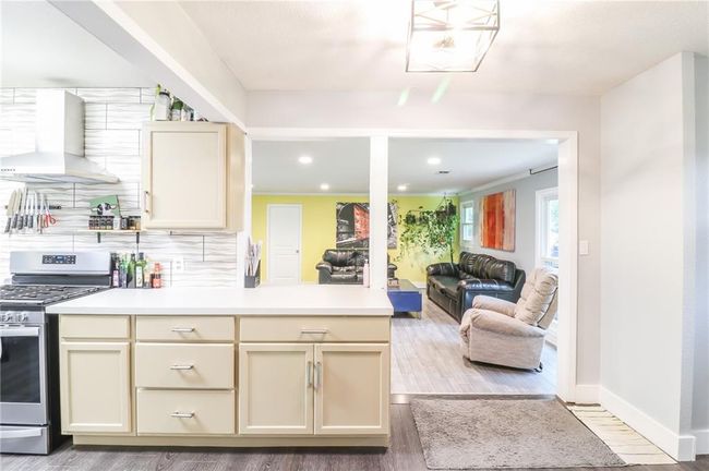 Kitchen featuring gas stove, wall chimney exhaust hood, cream cabinets, light countertops, and recessed lighting | Image 7