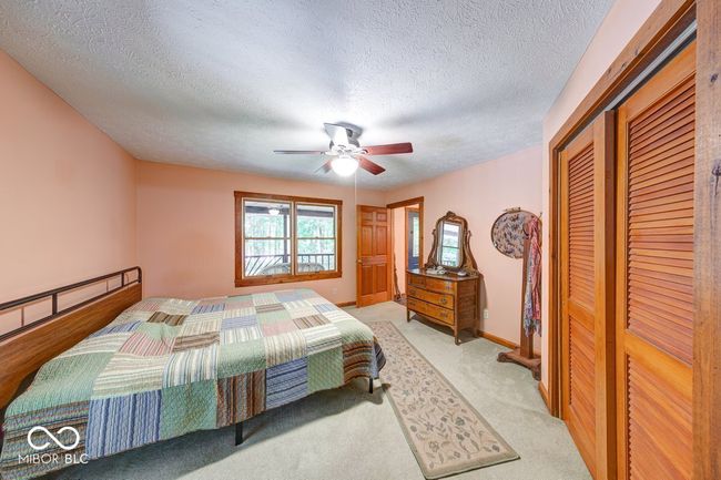bedroom featuring a textured ceiling, a closet, a ceiling fan, and light colored carpet | Image 26