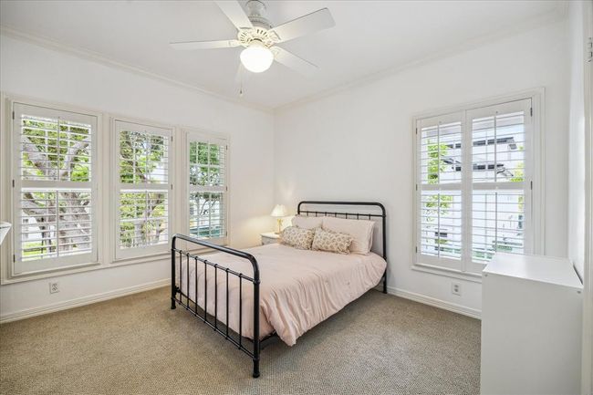 One of the secondary bedrooms with oversized windows with plantation shutters provides abundant natural light. This room features a built-in desk and walk-in closet as well. Hardwood floors that match the rest of the second story are under the carpet!!! | Image 25