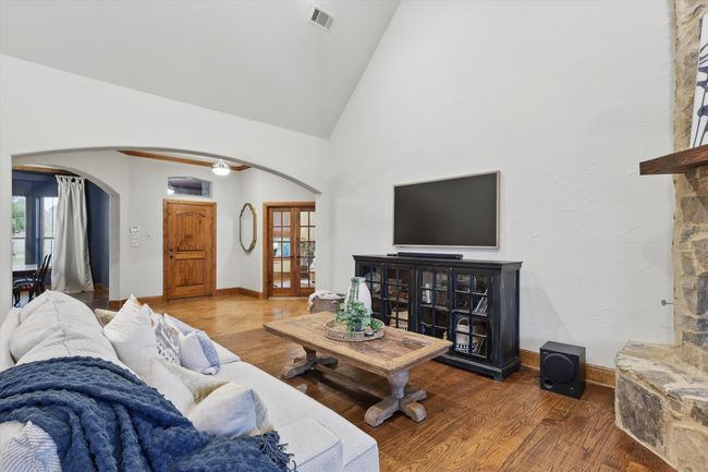 Living room with arched walkways, vaulted ceiling, and wood finished floors | Image 11
