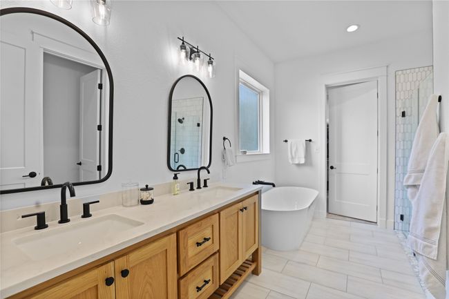 Full bathroom featuring an enclosed shower, a freestanding tub, a sink, and double vanity | Image 18