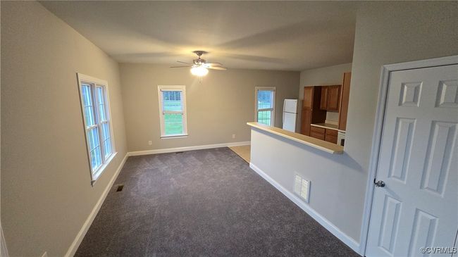 Unfurnished room with visible vents, baseboards, a ceiling fan, and dark carpet | Image 45
