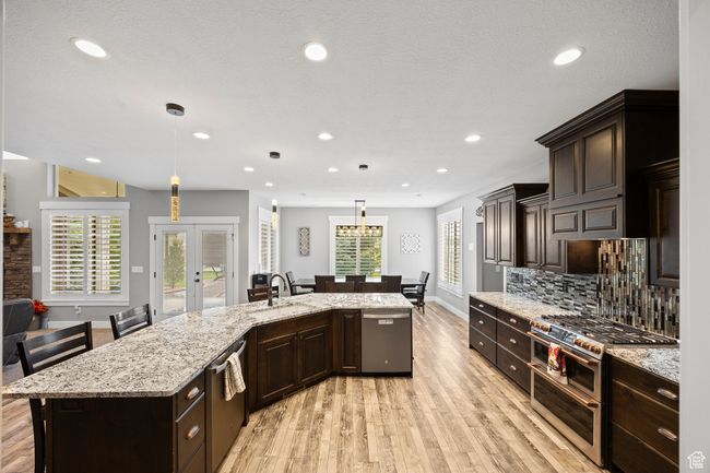 Kitchen featuring appliances with stainless steel finishes, a sink, light wood finished floors, tasteful backsplash, and dark brown cabinets | Image 24