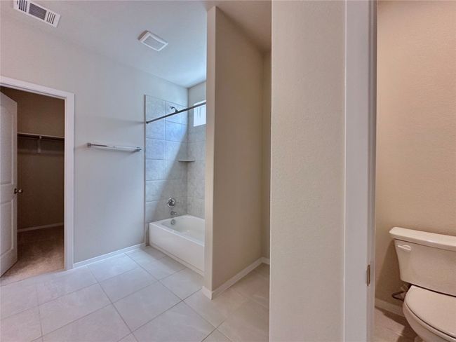 Bathroom featuring shower combination, tile patterned flooring, and a walk in closet | Image 13