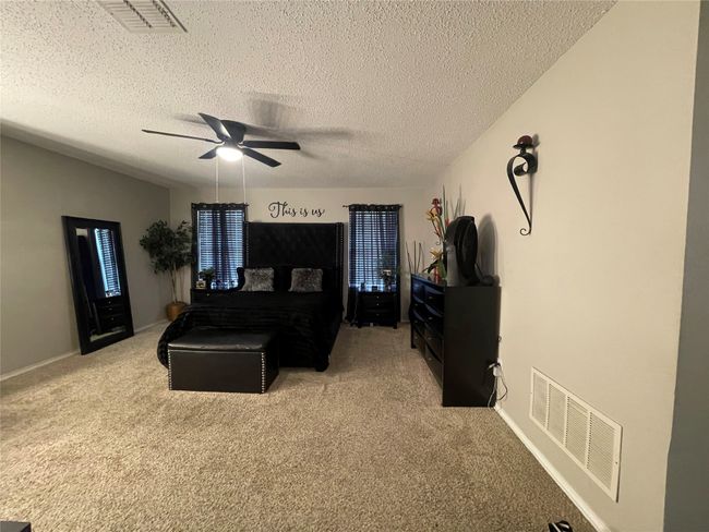 Bedroom featuring a textured ceiling, light carpet, and ceiling fan | Image 16
