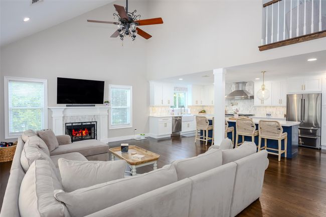 Living area featuring ceiling fan, high vaulted ceiling, dark wood-style floors, a lit fireplace, and recessed lighting | Image 10