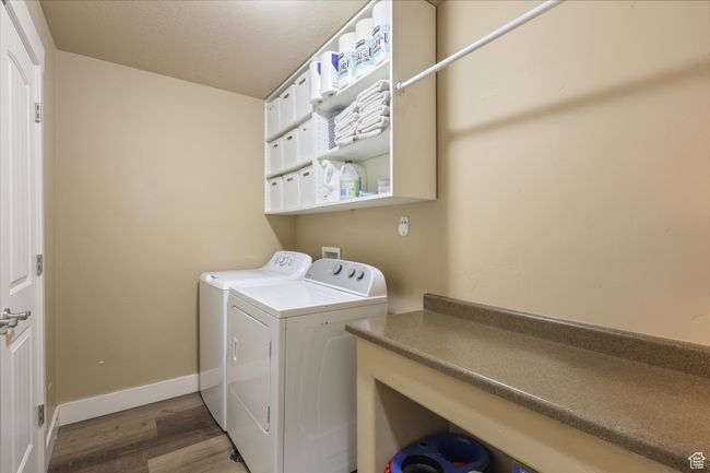 Laundry room with wood finished floors, washer and clothes dryer, laundry area, and baseboards | Image 8