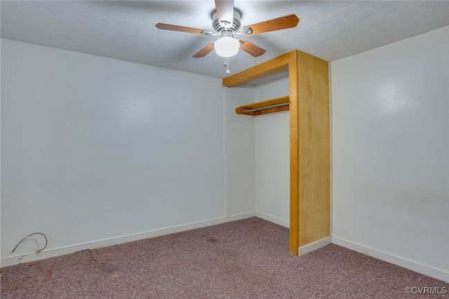 2nd unit bedroom with carpet flooring, a textured ceiling, ceiling fan, and a closet | Image 36