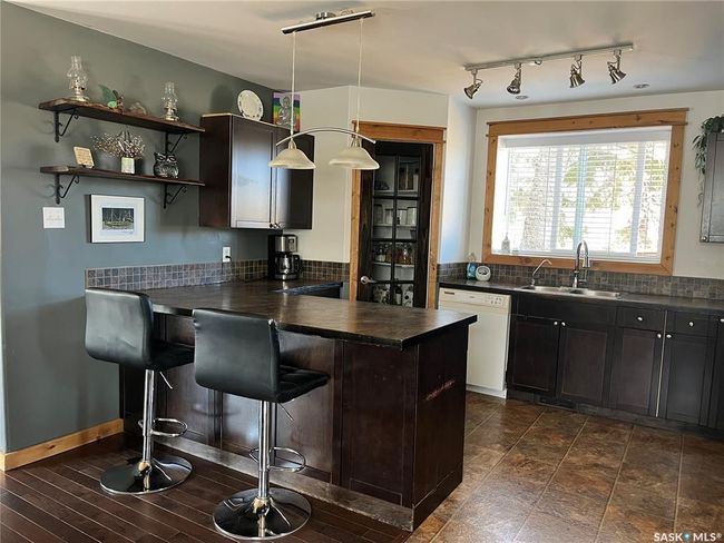 Kitchen featuring a sink, rail lighting, a peninsula, dark countertops, and dishwasher | Image 10