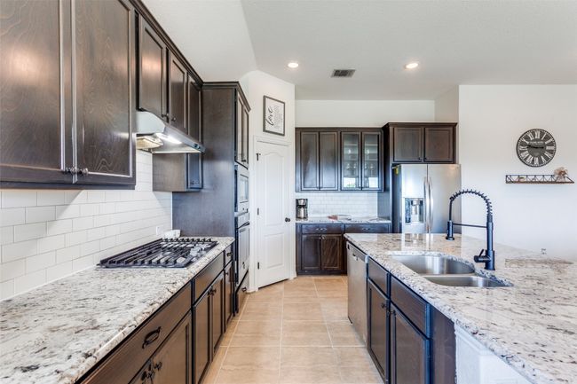 Kitchen with stainless steel appliances, light stone countertops, tasteful backsplash, dark brown cabinetry, and recessed lighting | Image 9