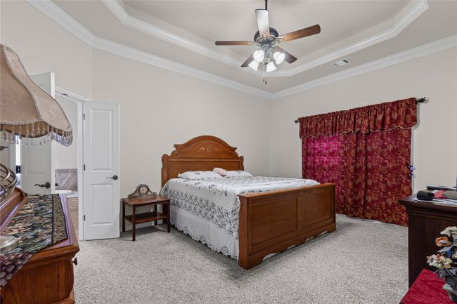 Bedroom featuring a tray ceiling, light colored carpet, ornamental molding, and a ceiling fan | Image 14