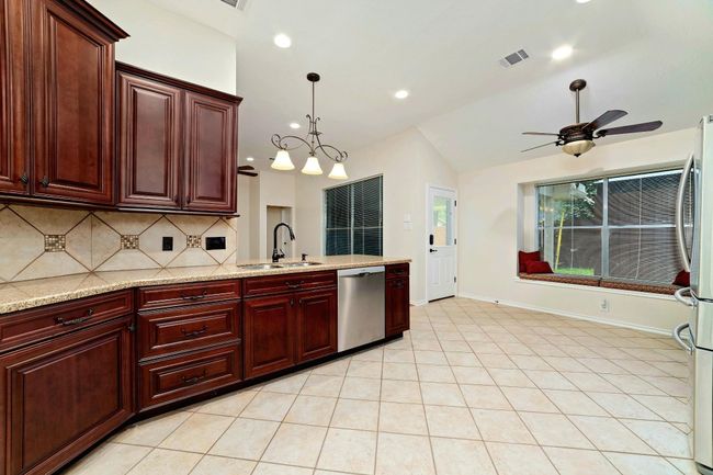 This kitchen is inviting in every sense—where timeless beauty meets effortless function. Elegant warm cabinetry offers abundant space, complemented by classic backsplashes and easy-to-maintain countertops that make everyday living a pleasure. | Image 11