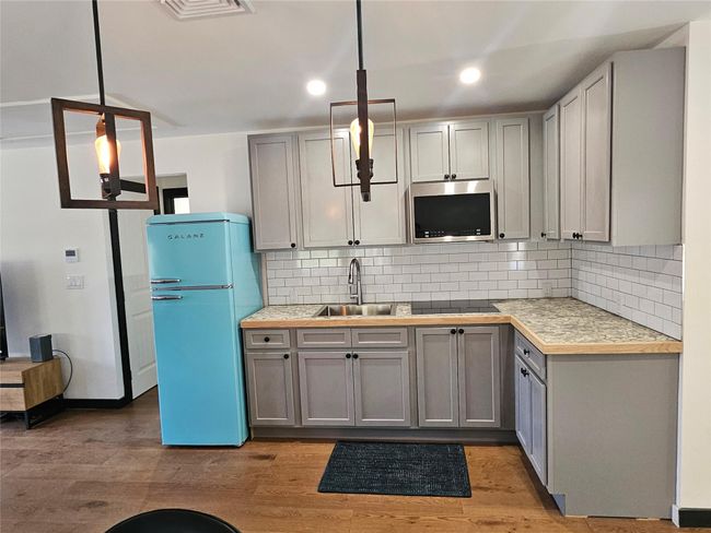 Kitchen with freestanding refrigerator, stainless steel microwave, a sink, gray cabinetry, and decorative backsplash | Image 15