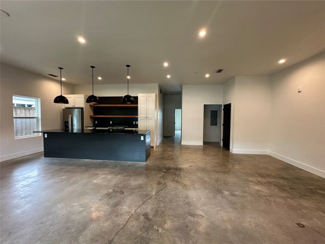 Kitchen featuring stainless steel fridge with ice dispenser, dark countertops, concrete flooring, recessed lighting, and white cabinets | Image 22