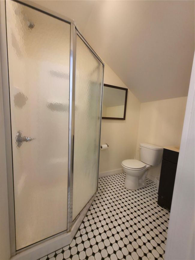 Bathroom with a stall shower, baseboards, lofted ceiling, and toilet | Image 15
