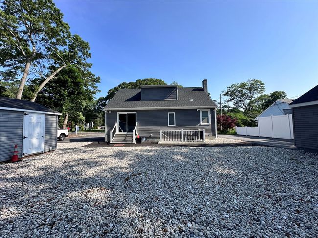 Rear view of property with a chimney, a storage shed, roof with shingles, and entry steps | Image 5