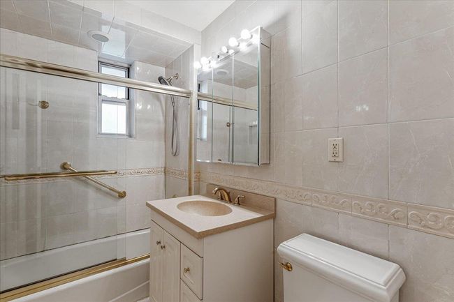 Full bath featuring vanity, shower / bath combination with glass door, and tile walls | Image 10