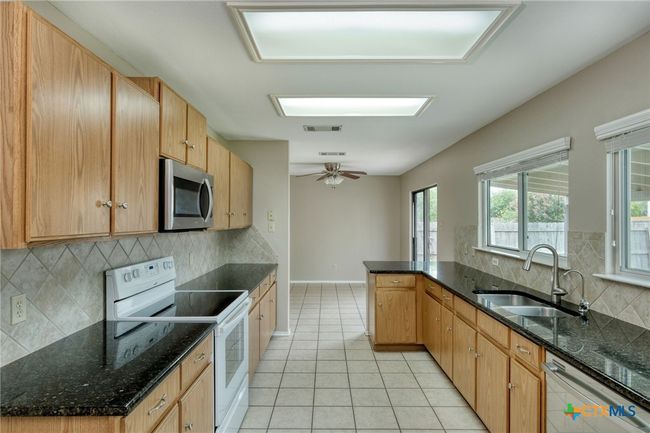 Galley style kitchen with breakfast bar, plenty of cabinetry, and lots of counterspace. | Image 13
