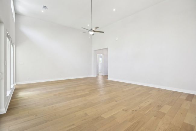 Empty room featuring a towering ceiling, light wood-type flooring, baseboards, a ceiling fan, and visible vents | Image 25