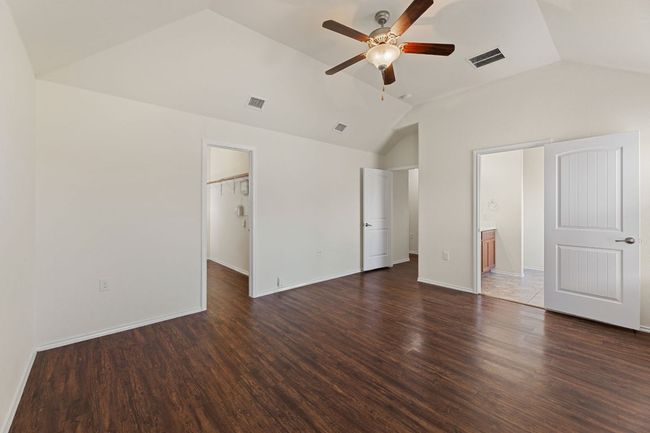 Unfurnished bedroom with lofted ceiling, dark wood finished floors, a spacious closet, and a ceiling fan | Image 22