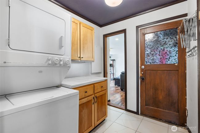 utility room with stackable unit, built-in cabinets and folding space | Image 11
