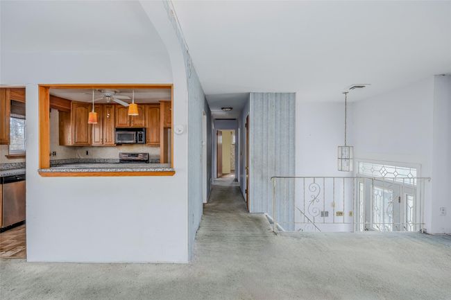 Kitchen with visible vents, brown cabinetry, decorative light fixtures, carpet, and stainless steel appliances | Image 6