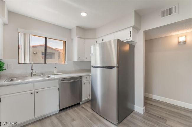 Kitchen with stainless steel appliances, light wood-type flooring, white cabinets, light countertops, and recessed lighting | Image 12