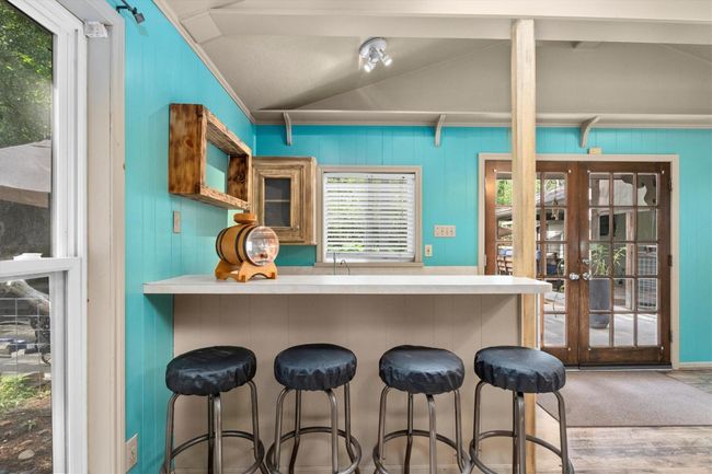 This cozy space features a charming wet bar area with natural light streaming through large windows and French doors, creating a warm and inviting atmosphere. | Image 21