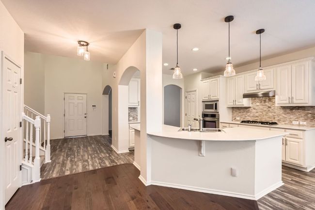 Kitchen featuring arched walkways, appliances with stainless steel finishes, backsplash, dark wood-style floors, and recessed lighting | Image 28