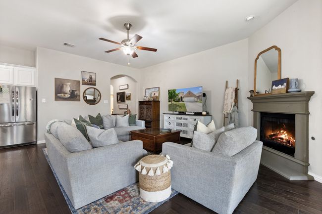 Living area with a glass covered fireplace, arched walkways, dark wood-type flooring, and ceiling fan | Image 8