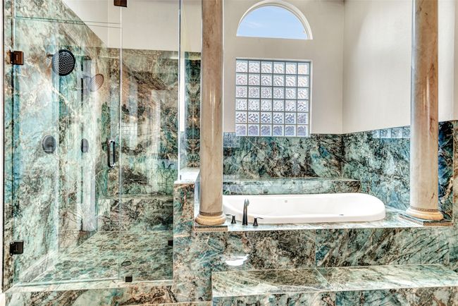Double shower heads in the oversized shower help you relax, as will the deep jetted tub surrounded by impressive columns and snuggled under a glass block window. | Image 24