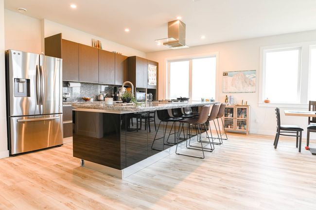 Kitchen featuring stainless steel fridge with ice dispenser, a kitchen breakfast bar, light wood-style floors, decorative backsplash, and recessed lighting | Image 18