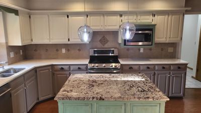 Kitchen with light stone counters, sink, dark wood-type flooring, appliances with stainless steel finishes, and a center island | Image 3