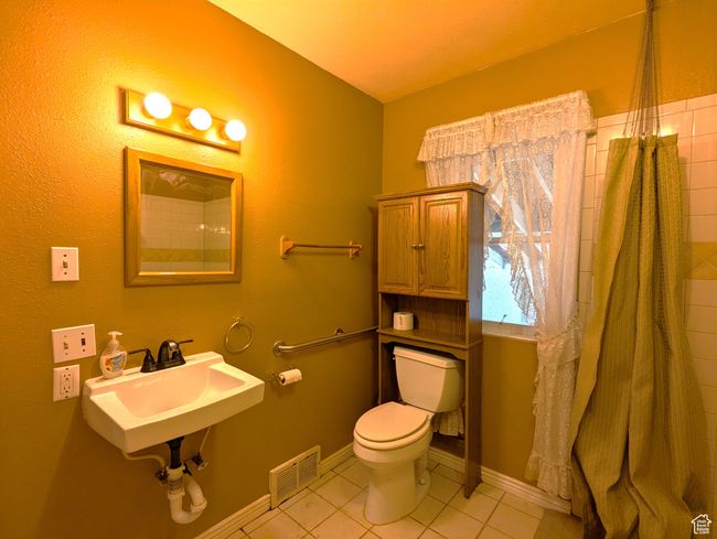 Bathroom with baseboards, visible vents, a sink, tile patterned flooring, and toilet | Image 12