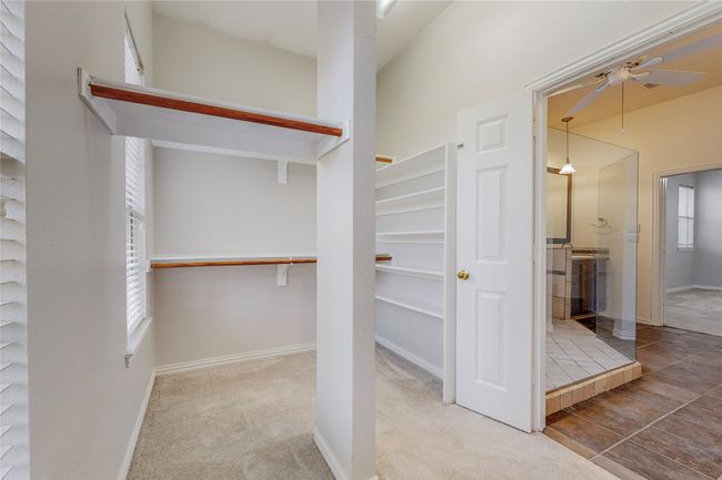 Spacious closet with a ceiling fan and carpet flooring | Image 25