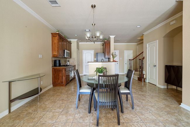 Dining room featuring a notable chandelier, crown molding, stairs, visible vents, and baseboards | Image 25