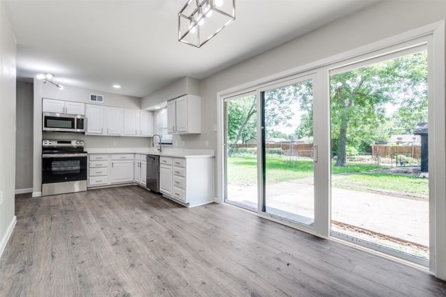 Kitchen featuring appliances with stainless steel finishes, light countertops, light wood-style flooring, and white cabinets | Image 14