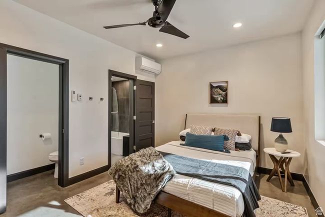 Bedroom with baseboards, connected bathroom, a wall unit AC, finished concrete floors, and recessed lighting | Image 60