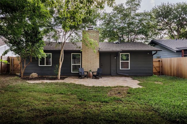 Rear view of property with a chimney, a patio area, a fenced backyard, a shingled roof, and a gate | Image 31
