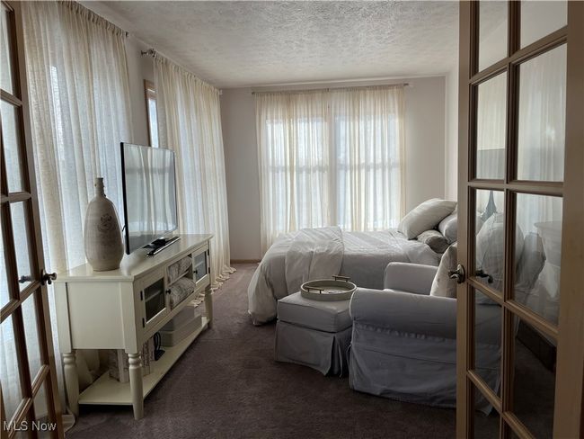 Second Bedroom on First Floor has multiple windows, french doors, and a textured ceiling | Image 8