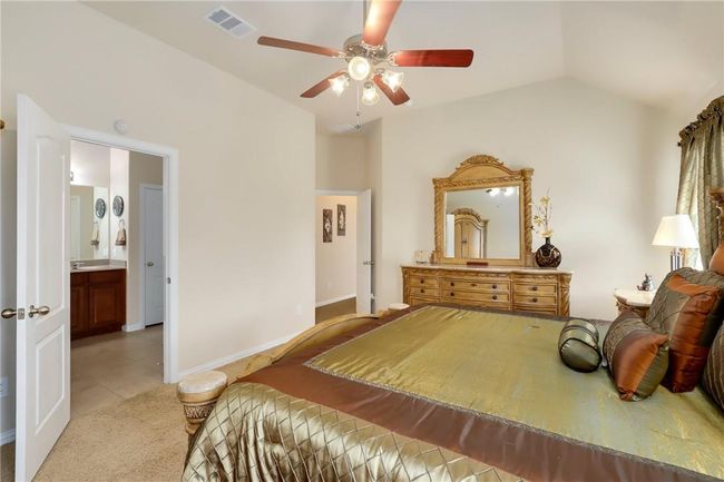 Bedroom with light tile patterned floors, vaulted ceiling, ceiling fan, light colored carpet, and baseboards | Image 13