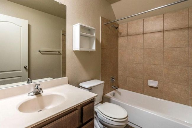 Full bathroom featuring toilet, vanity, tub / shower combination, and a textured wall | Image 21