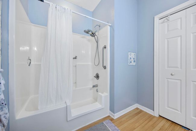 Bathroom featuring shower / bath combo, wood finished floors, and baseboards | Image 21
