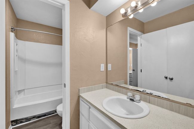 Bathroom featuring toilet, vanity, bathing tub / shower combination, and wood finished floors | Image 10
