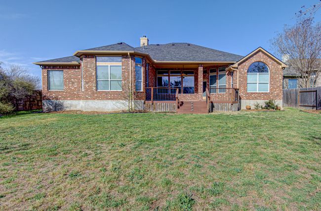 Back of property with brick siding, a porch, a lawn, and fence | Image 31
