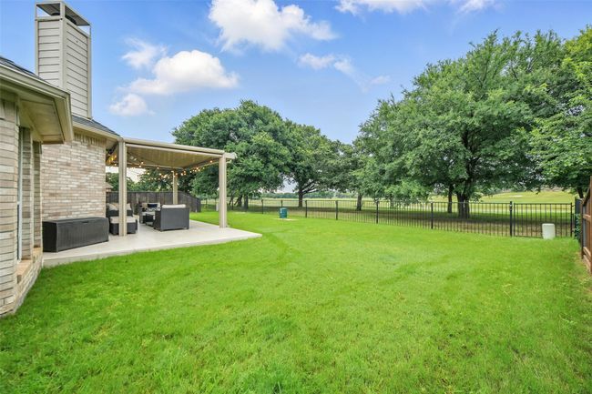 Fenced backyard with an outdoor hangout area, a patio area, and a ceiling fan | Image 31