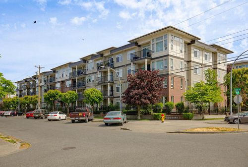 Multi-story residential building featuring light-colored siding and brick accents | Card Image