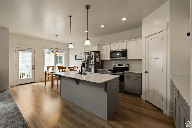 Kitchen with dark wood finished floors, a sink, a kitchen bar, appliances with stainless steel finishes, and a notable chandelier | Image 4